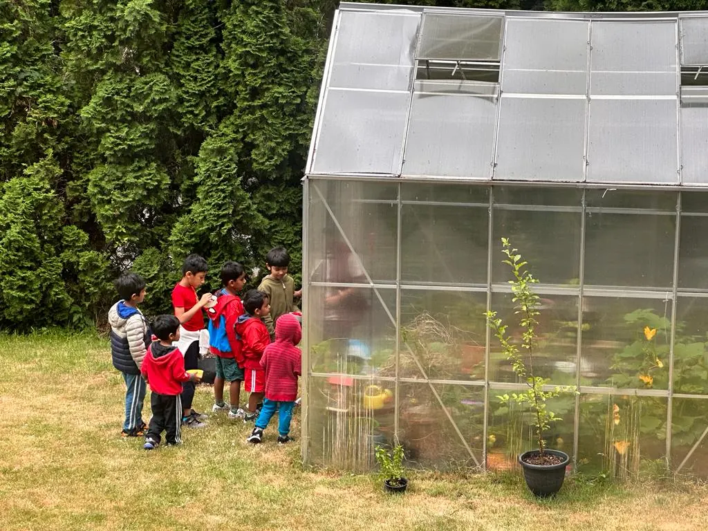Children gathered by the campus greenhouse