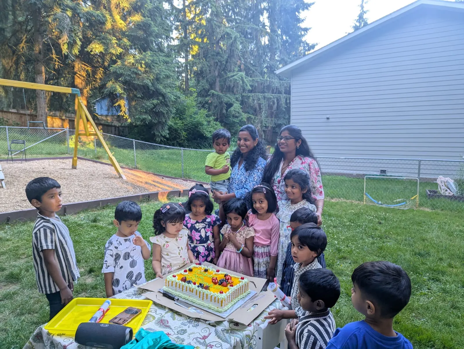 Children gathered around a celebration cake with their teachers