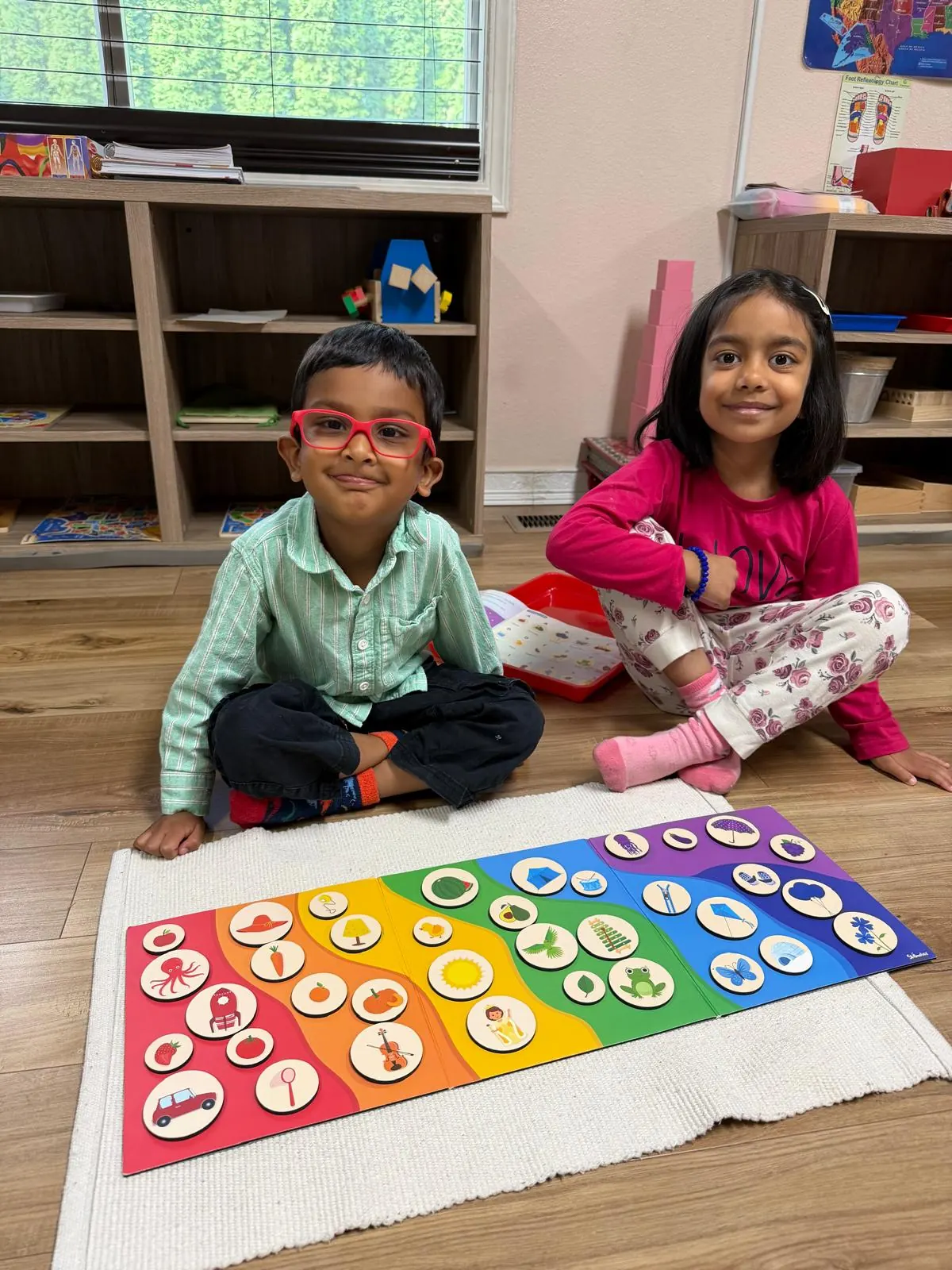 Two children proud of their rainbow colour-sorting board