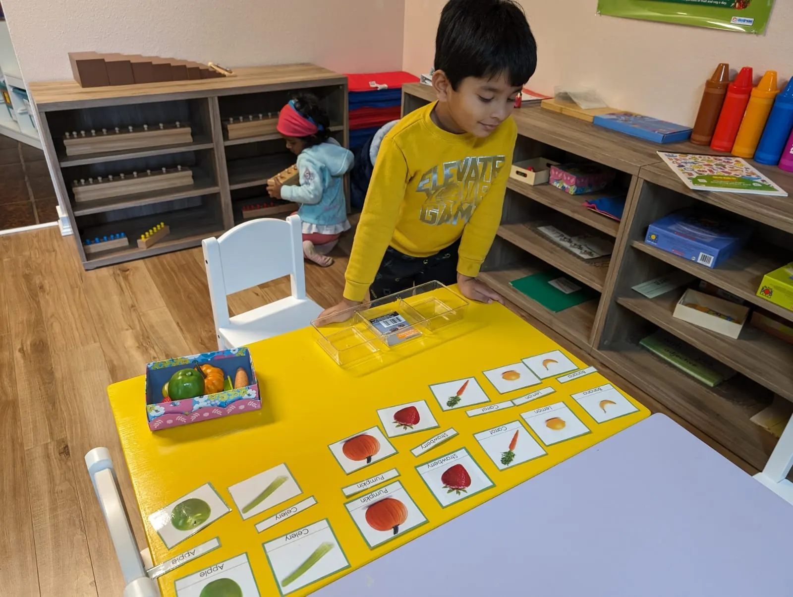 A child matching picture cards at a yellow table