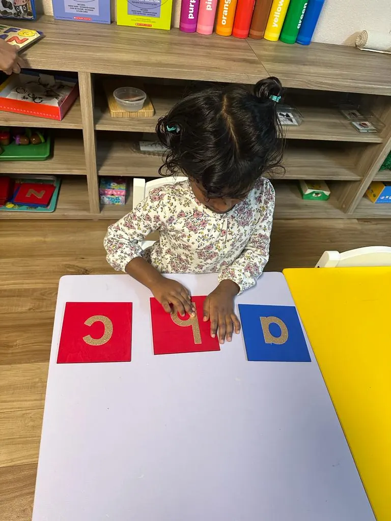 A child tracing sandpaper letters