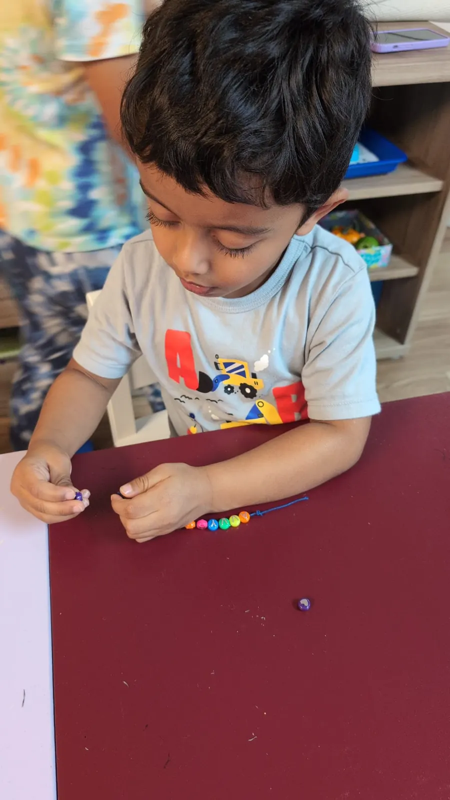 A child threading beads at a table