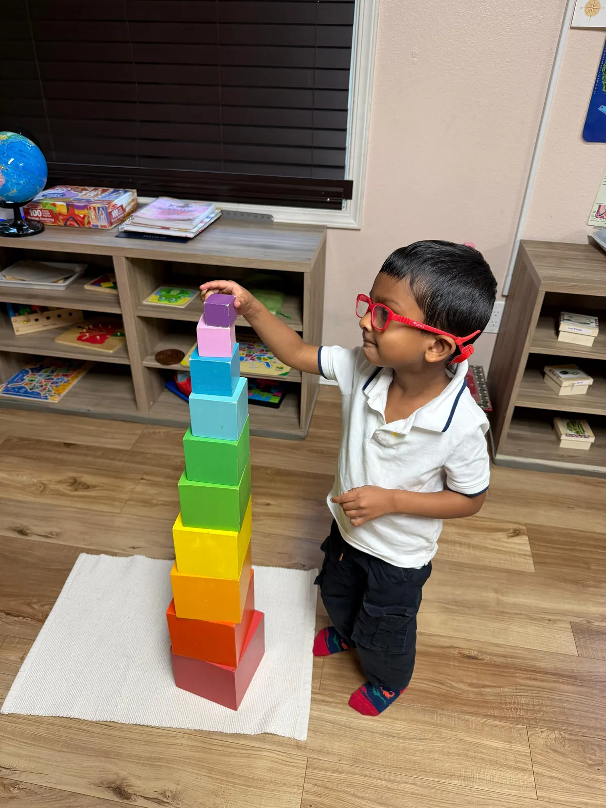 A boy placing the last block on a tall rainbow tower
