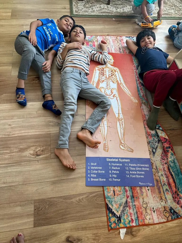 Children lying beside a life-size skeletal system chart