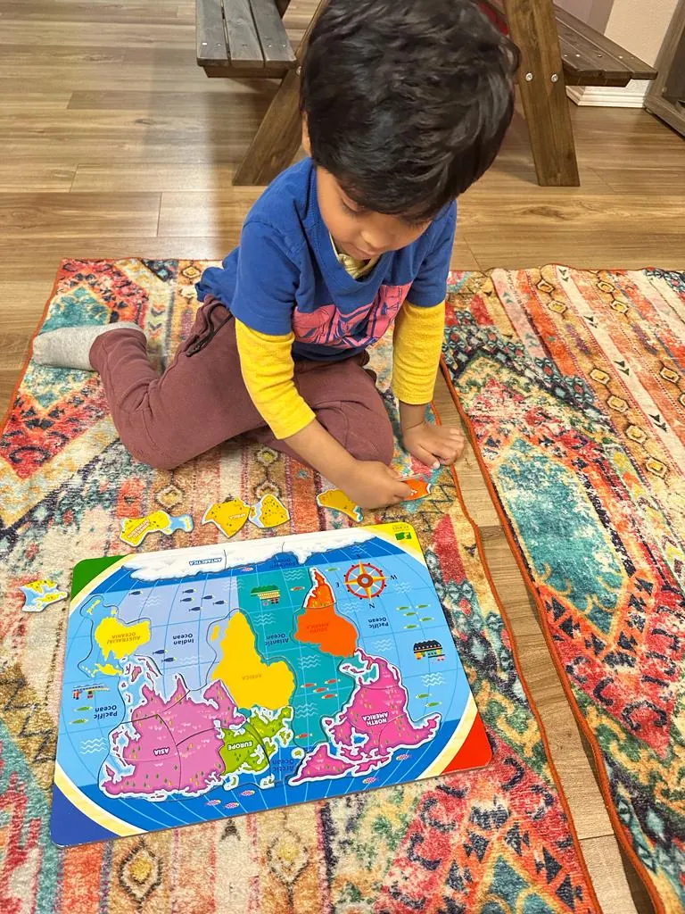A child building a world map puzzle on a rug