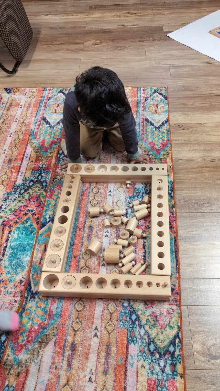 A child arranging wooden blocks on a rug