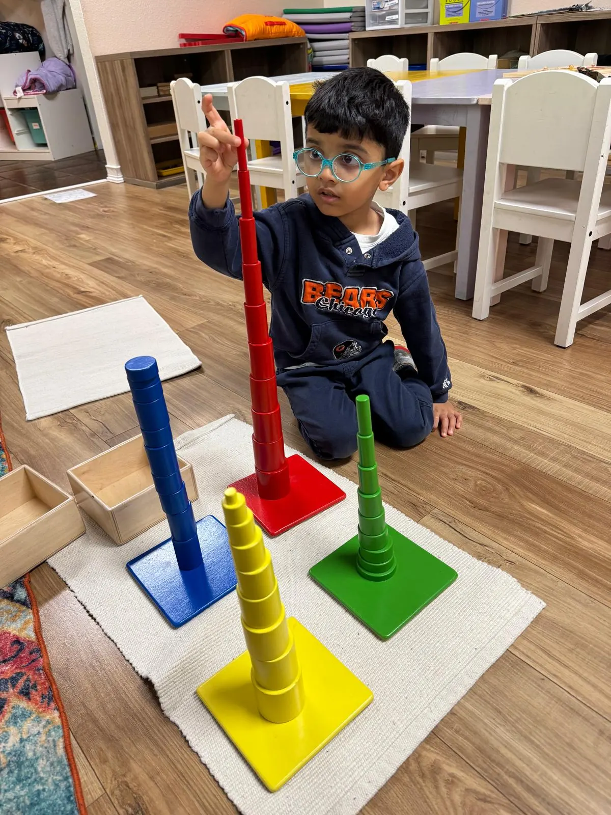 A boy comparing the heights of the coloured cylinder towers