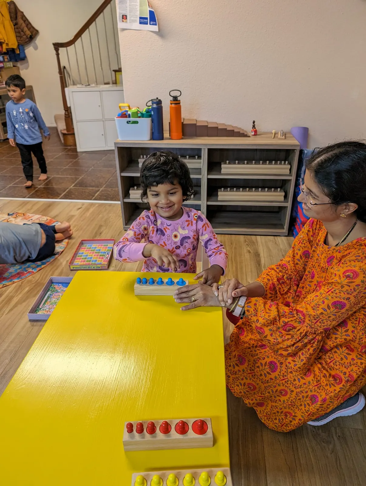 A teacher guiding a child through the knobbed cylinders