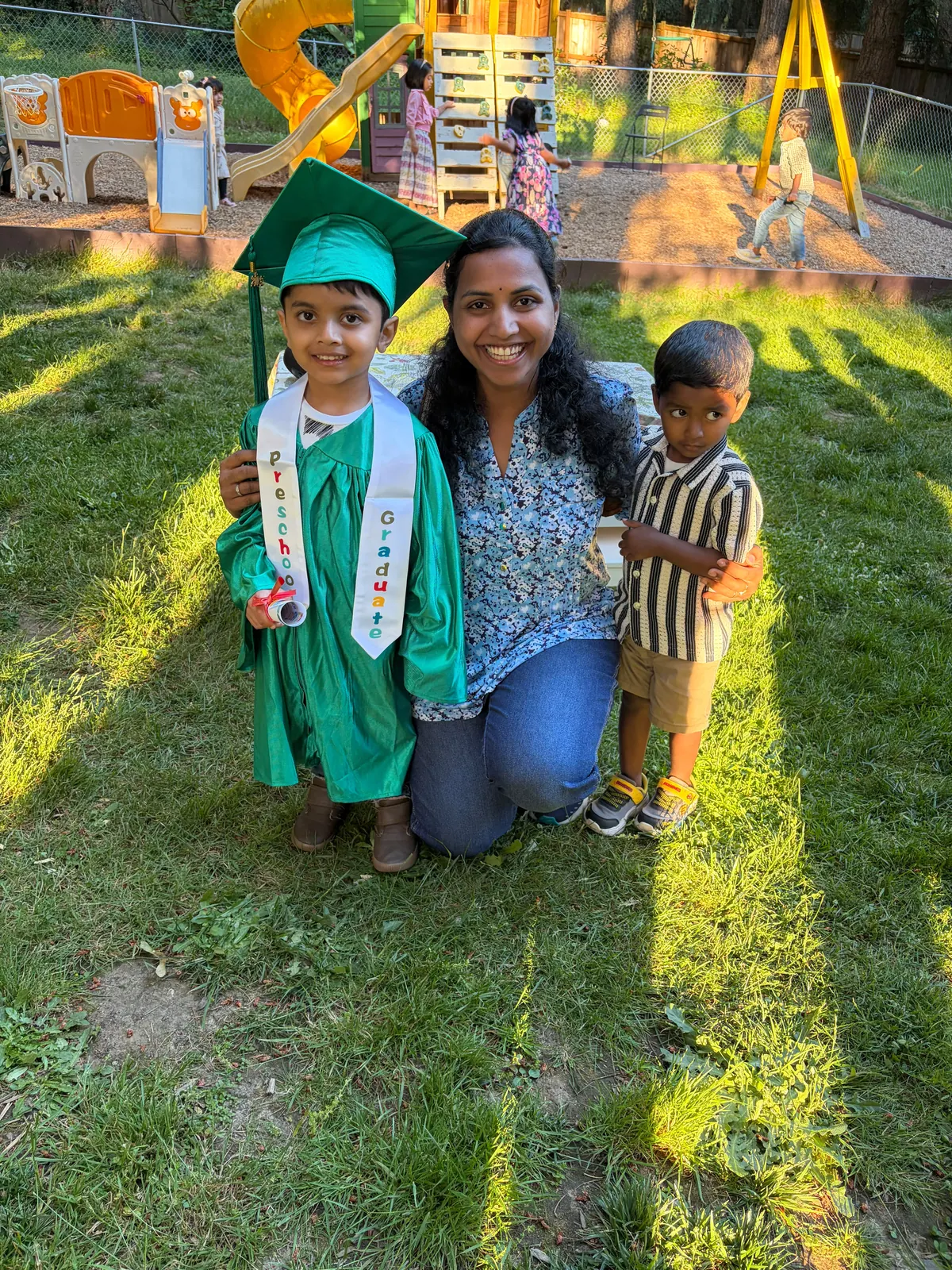 A graduate, his teacher and a younger friend on the lawn