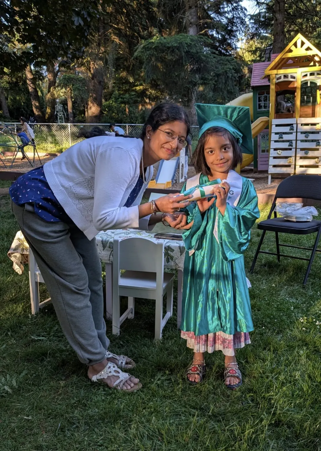 A teacher handing a graduate her rolled-up diploma