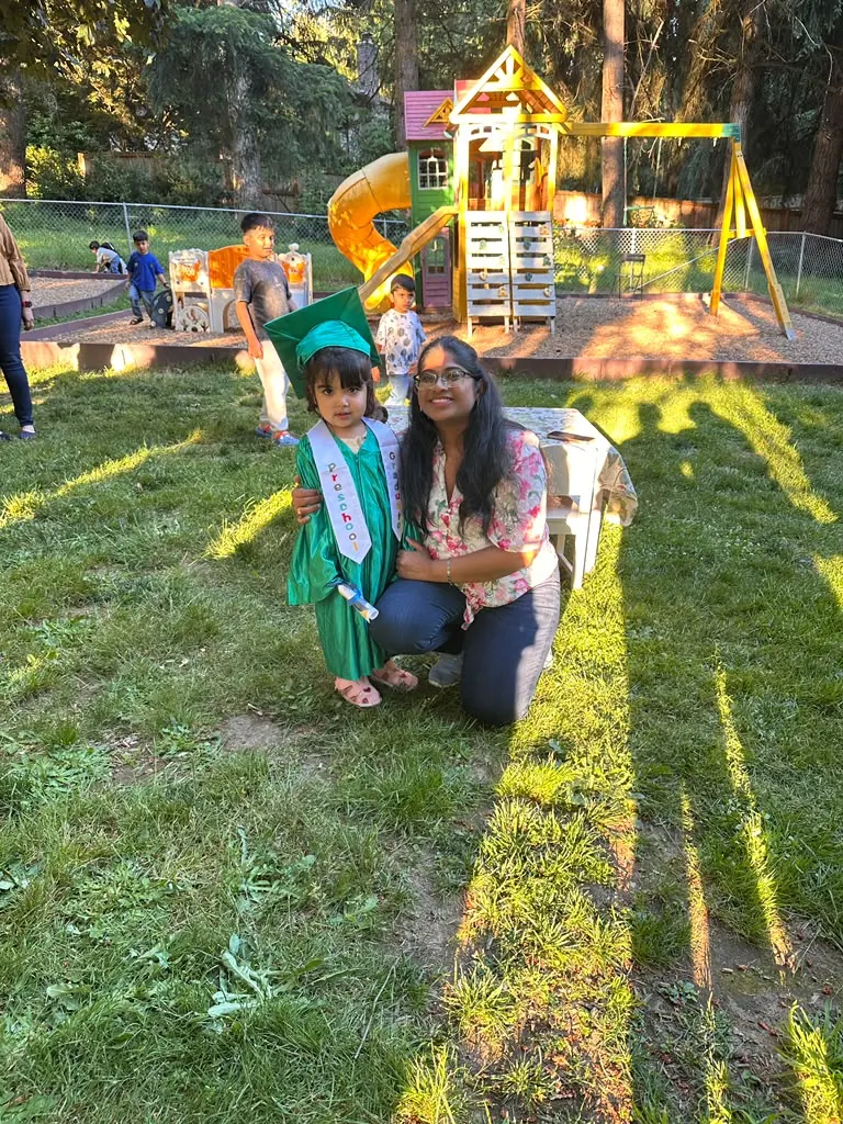 A small graduate and her teacher in the evening sun by the playground