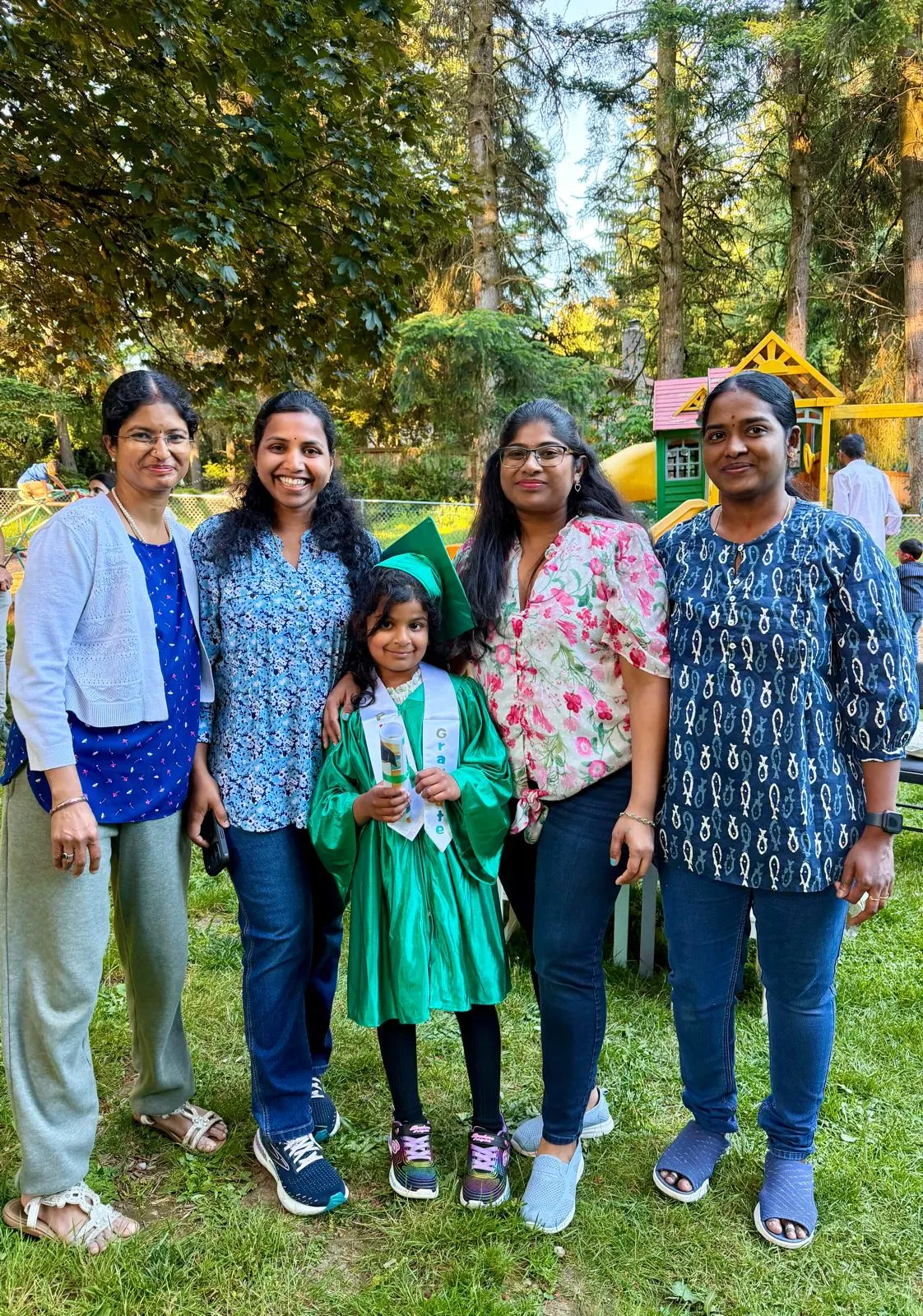 Four Gopa teachers with a graduate in a green cap and gown