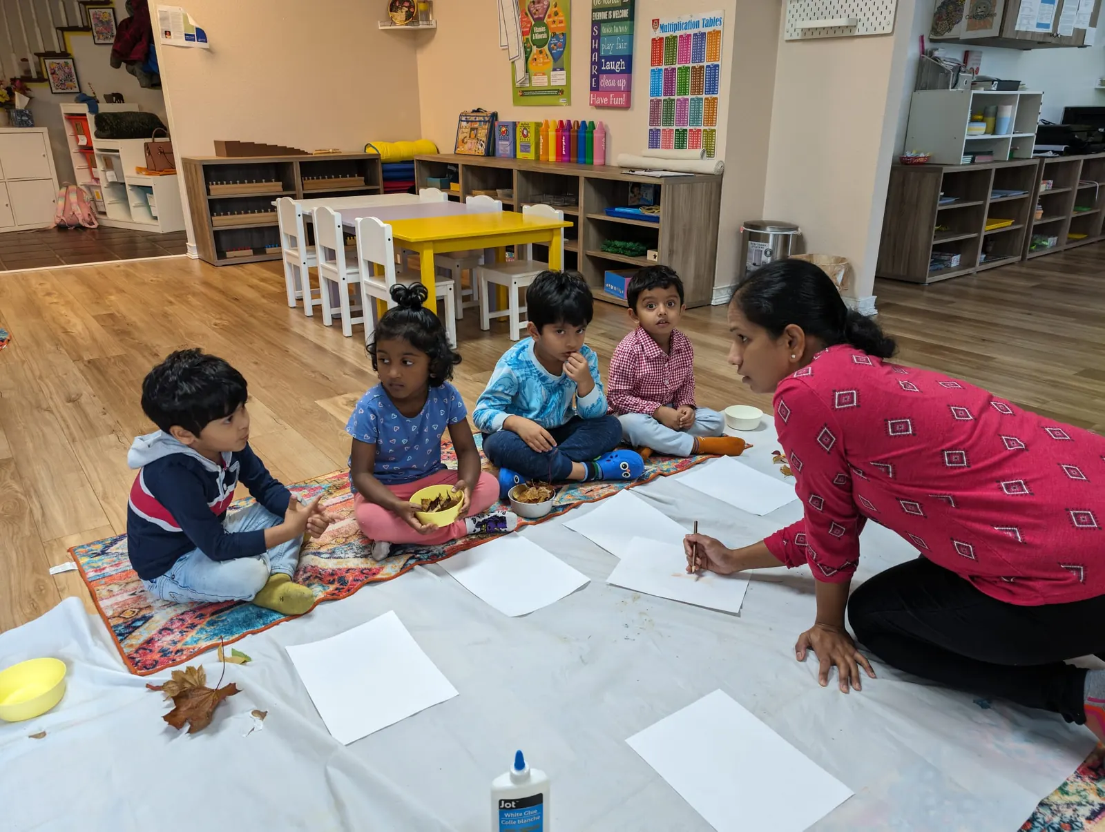 A teacher leading a craft session on the floor