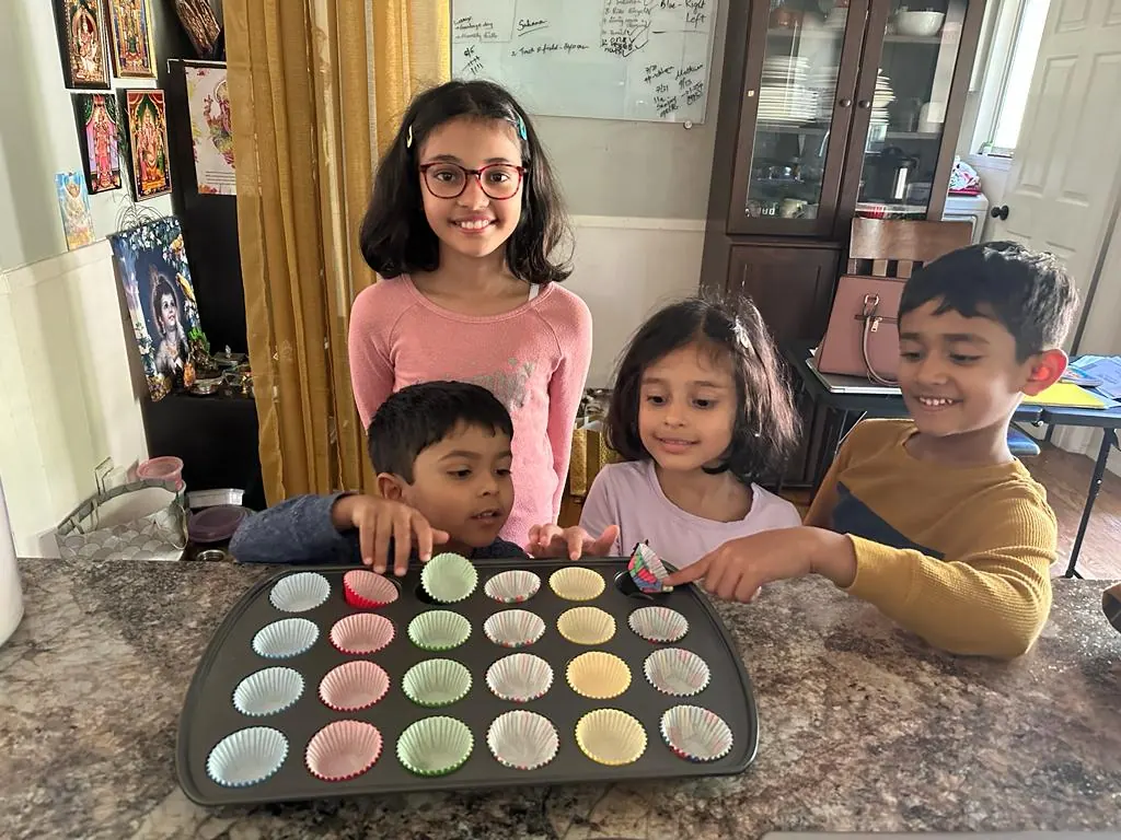 Children filling a cupcake tray