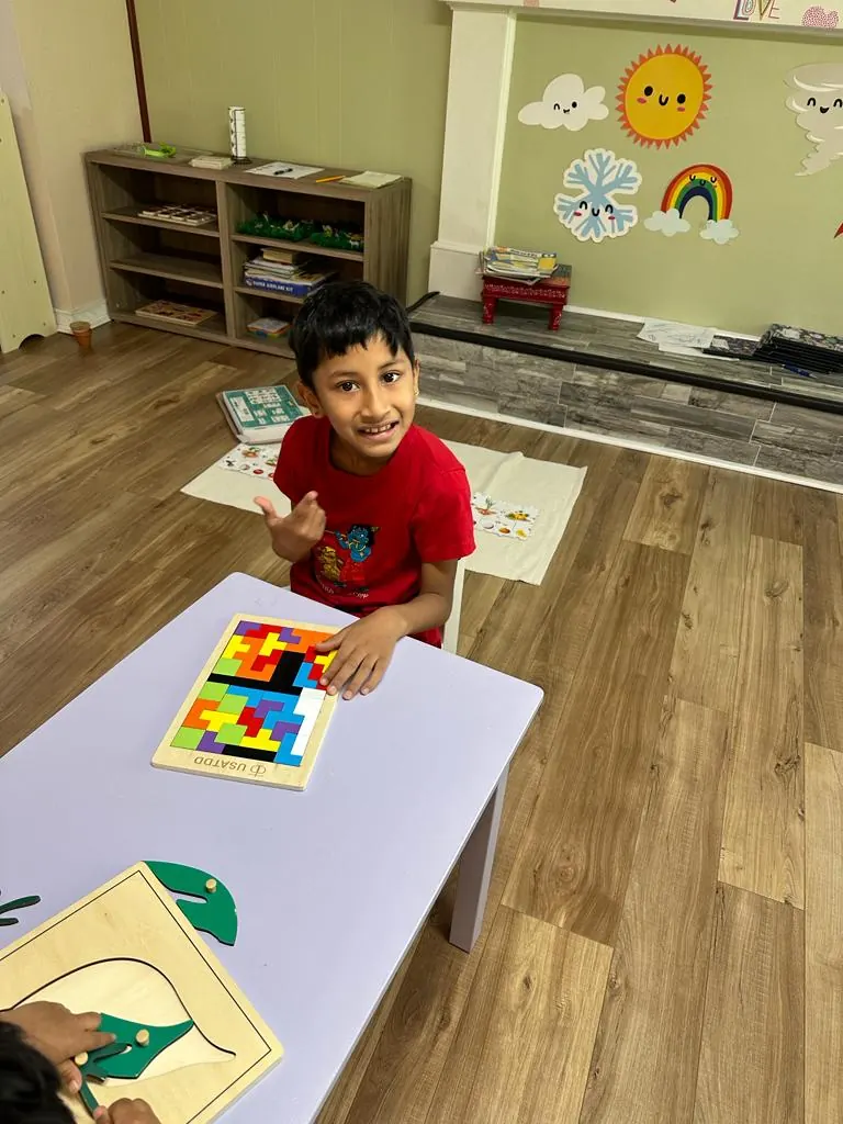 A boy smiling over a tangram puzzle