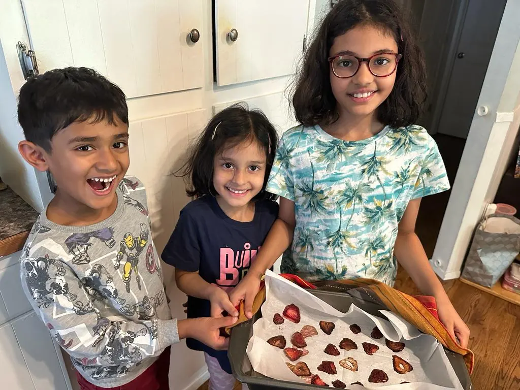 Children showing off a plate of strawberries