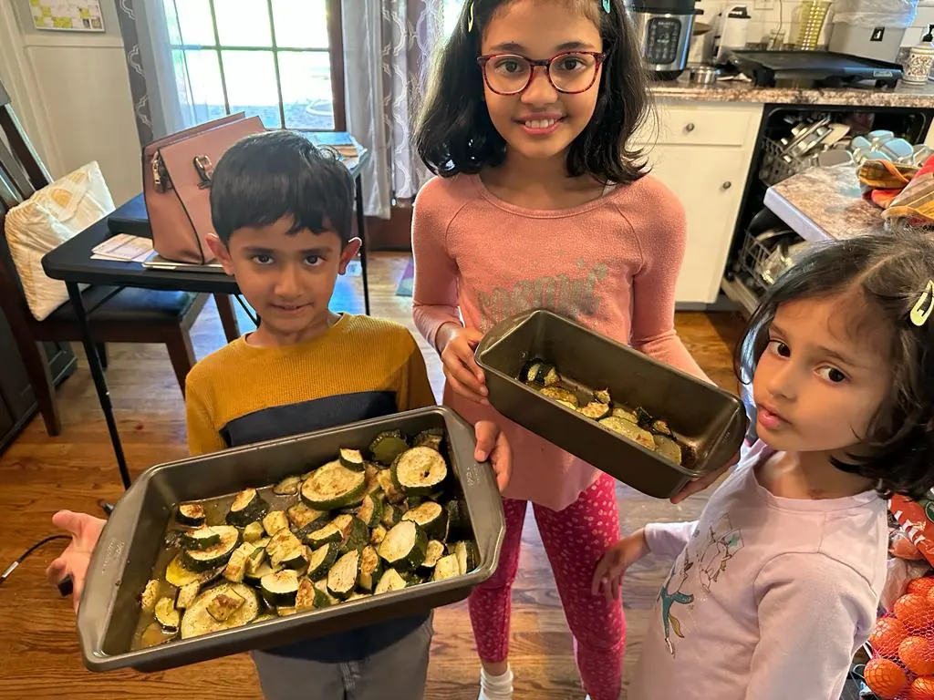 Children holding trays of baked zucchini